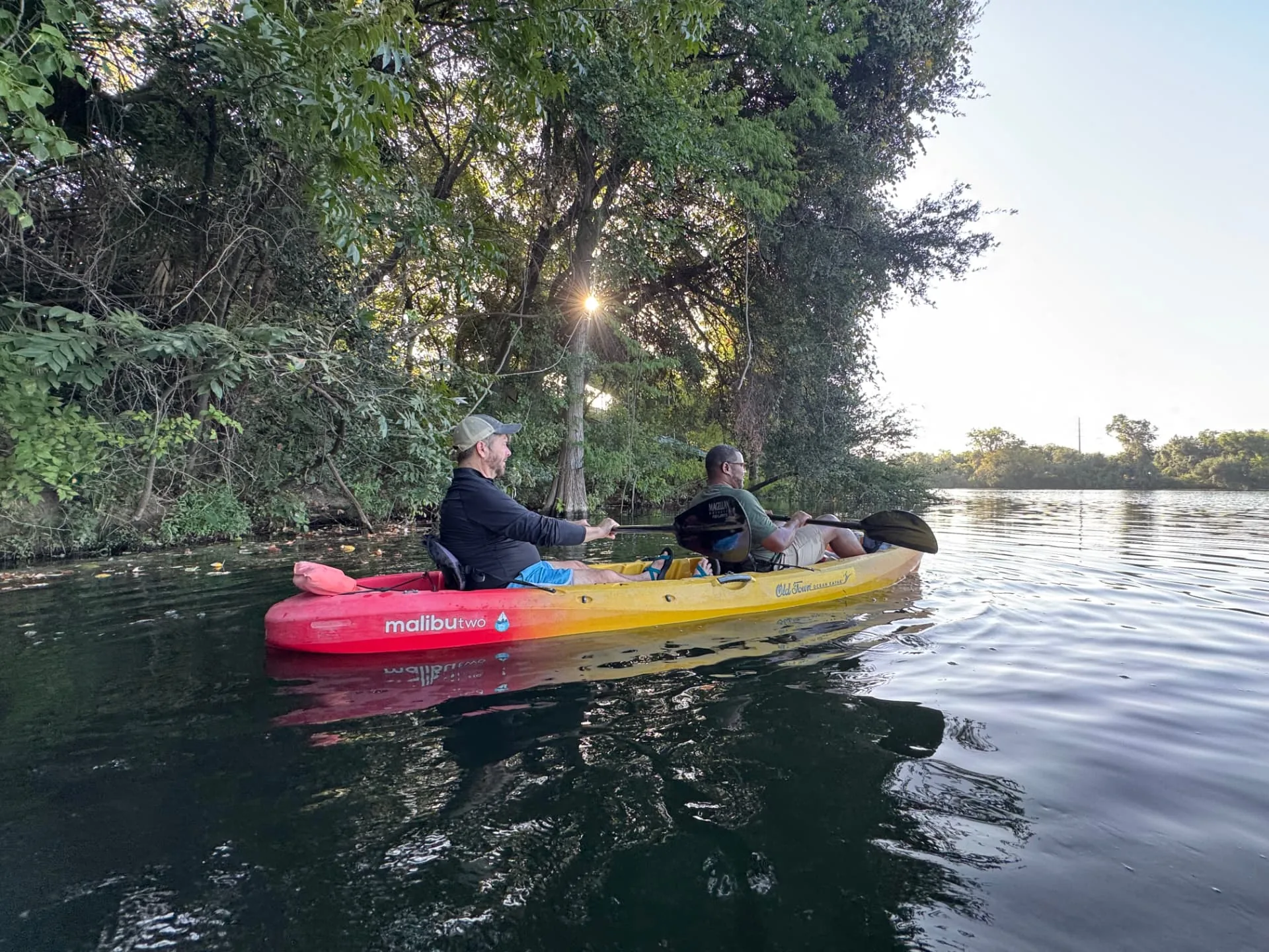 Two organizational leaders paddling a tandem kayak together at golden hour